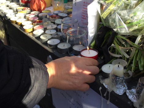 A woman places a candle at the memorial at Place de la Republique. ©Lisa Anselmo