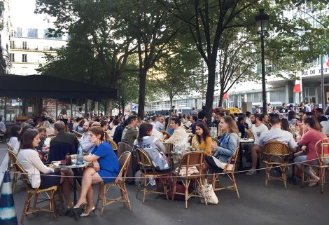 A crowd of people sitting on a plaza in Paris.