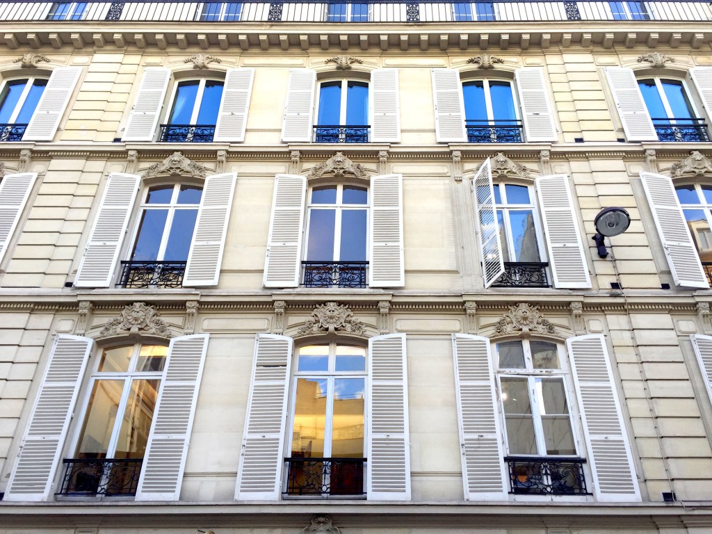 Facade of a Paris apartment building with white shutters