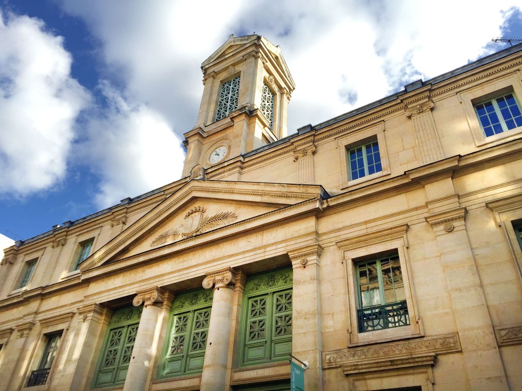 White stone church in Paris with a clock tower under a blue sky