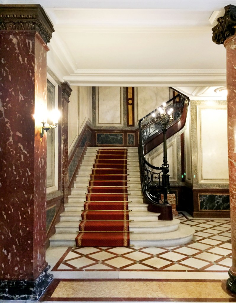 Marble lobby of a building in Paris with sweeping staircase